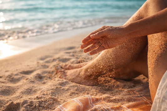sable sur main pieds jambe serviette plage mer